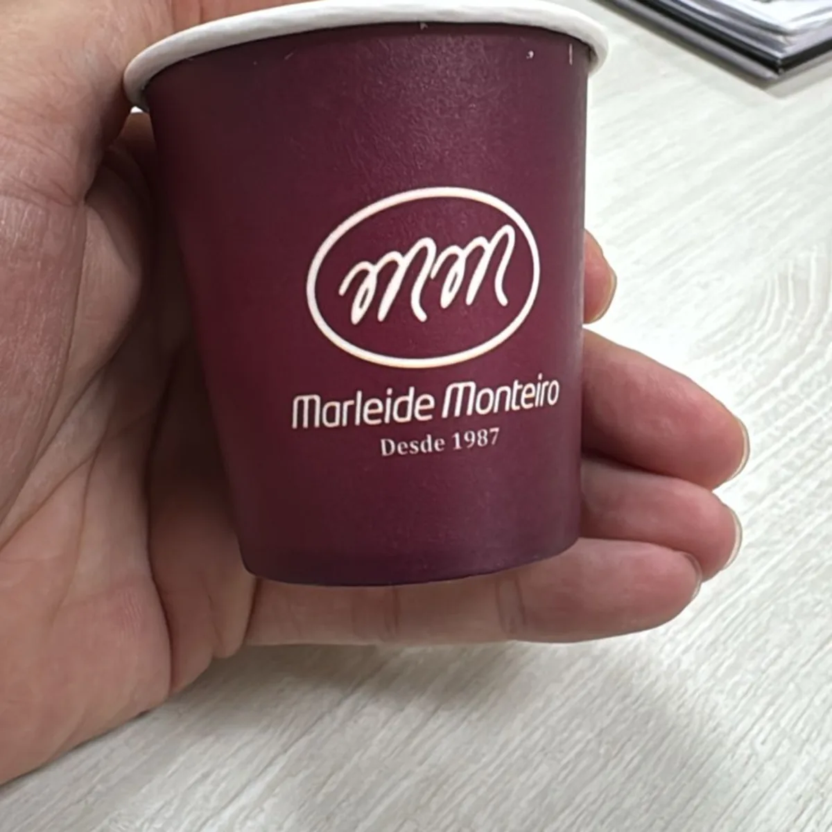 Copo de papel colorido com impressão branca, segurado na mão